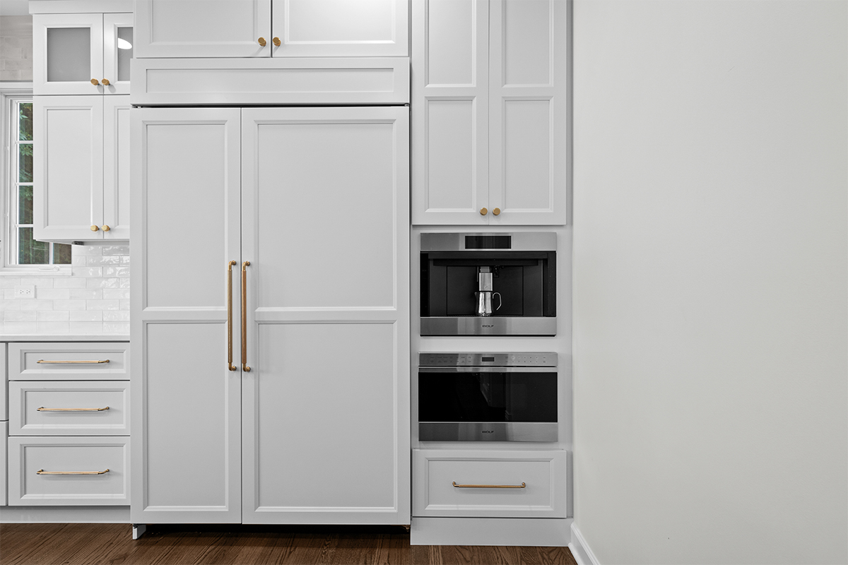 kitchen with white refrigerator panels attached with a double oven cabinet to the right.