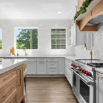 kitchen with white perimeter and stained rift white oak island cabinets.