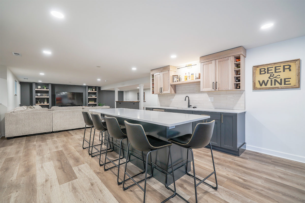 Contemporary kitchen with living room with large tv with open shelves on each side in the distance.