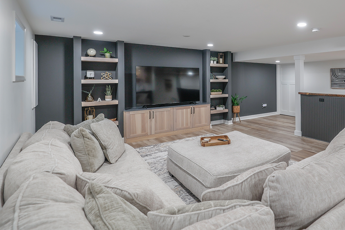 Entertainment center with large tv above light stained cabinets and open shelving on each side.