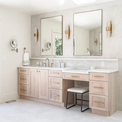 Light stained bathroom vanity with powder desk and two contemporary mirrors.
