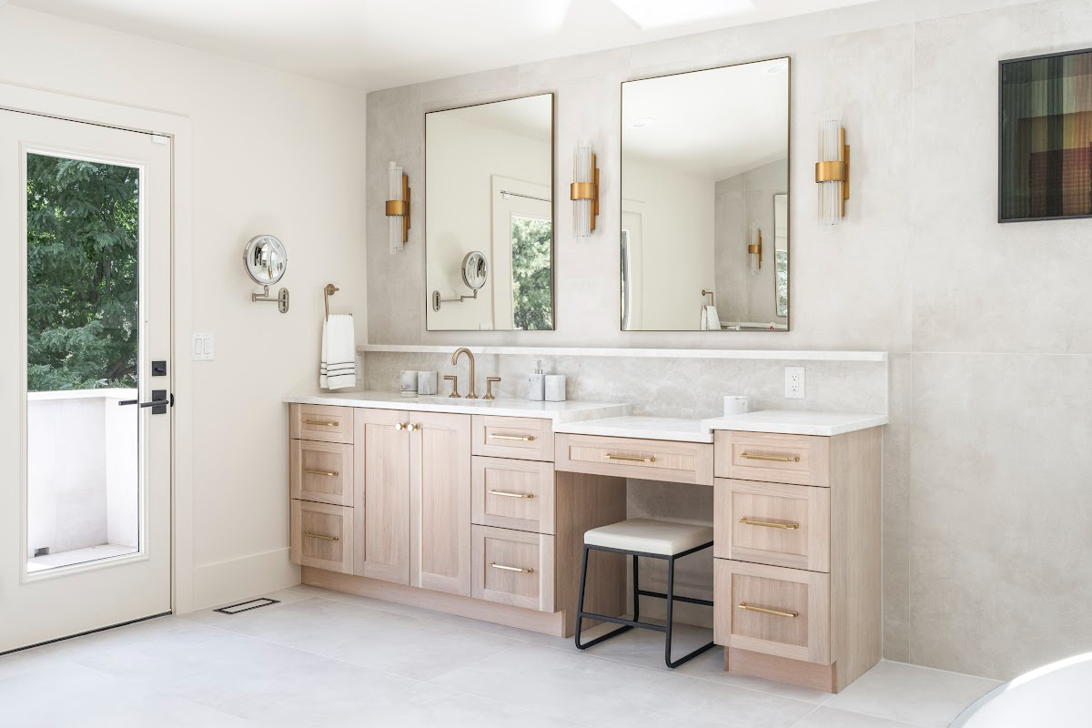 Light stained bathroom vanity with powder desk and two contemporary mirrors.