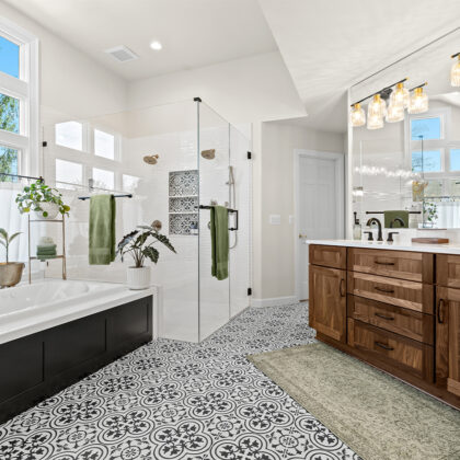 Bright and airy bathroom with several windows above the tub and warm brown stained double sink vanity with large mirror above.