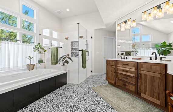 Bright and airy bathroom with several windows above the tub and warm brown stained double sink vanity with large mirror above.