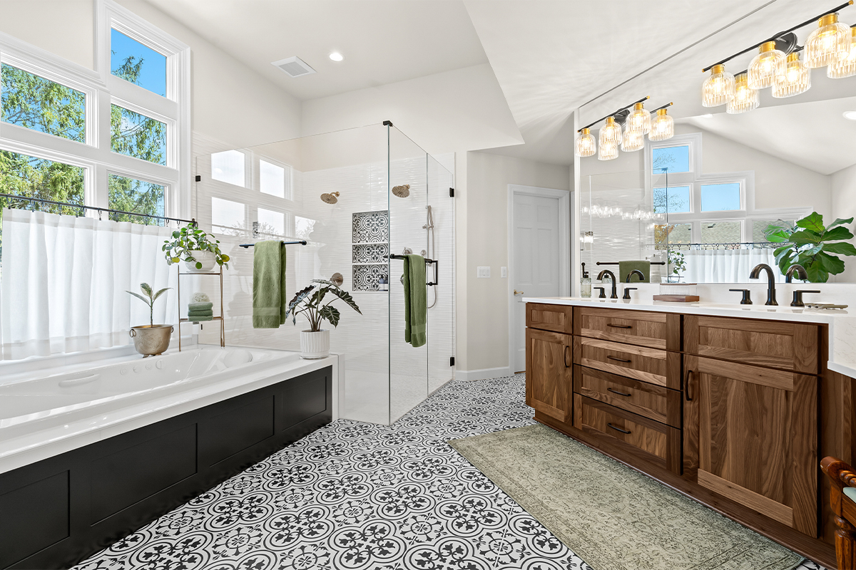 Bright and airy bathroom with several windows above the tub and warm brown stained double sink vanity with large mirror above.