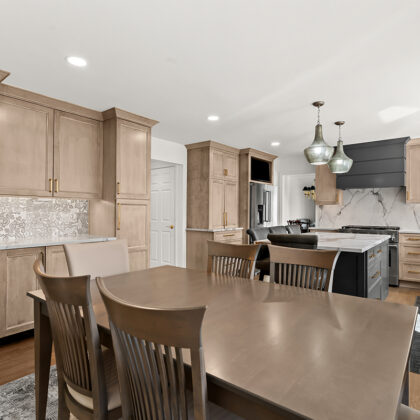 Kitchen cabinets with light brown stain. Shows a gray painted wood hood and stainless steel oven.
