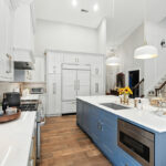 White kitchen perimeter cabinets with blue island.