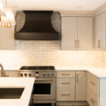Light Mocha painted perimeter kitchen cabinets and an island with dark stained hood and island.