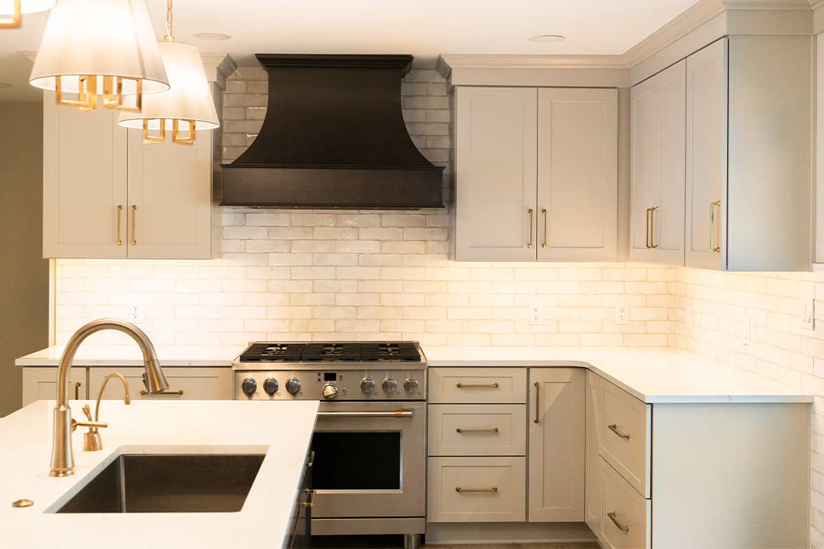 Light Mocha painted perimeter kitchen cabinets and an island with dark stained hood and island.