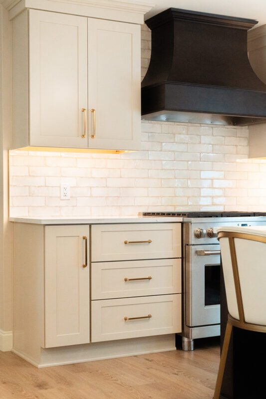 Light Mocha painted perimeter kitchen cabinets and an island with dark stained hood and island.