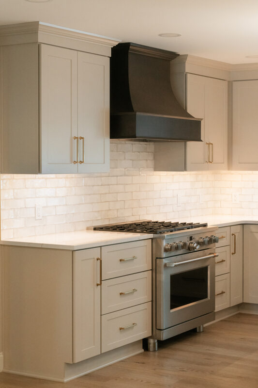 Light Mocha painted perimeter kitchen cabinets and an island with dark stained hood and island.