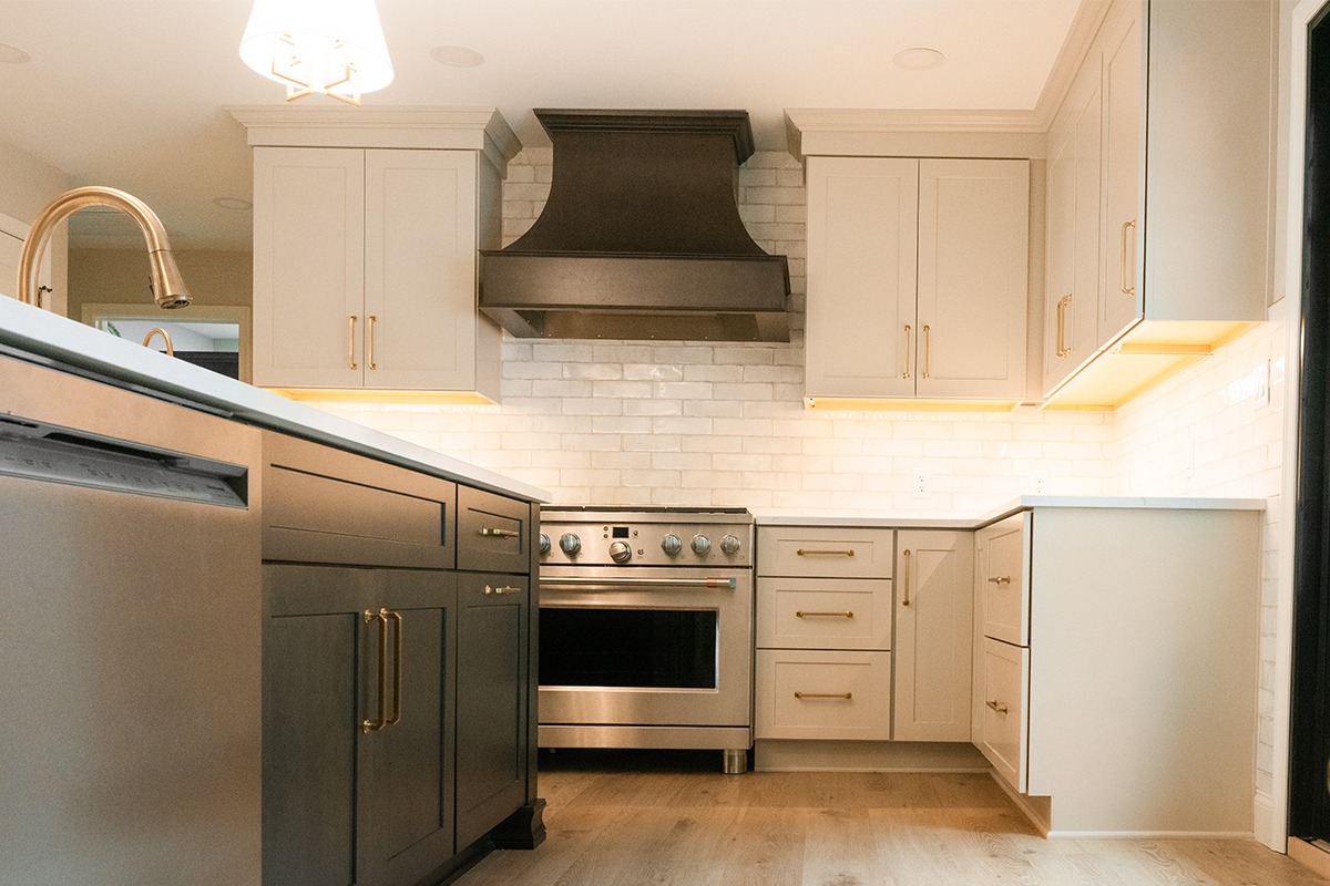Light Mocha painted perimeter kitchen cabinets and an island with dark stained hood and island.
