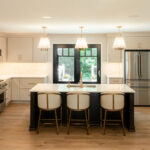 Light Mocha painted perimeter kitchen cabinets and an island with dark stained hood and island.