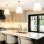 Light Mocha painted perimeter kitchen cabinets and an island with dark stained hood and island.