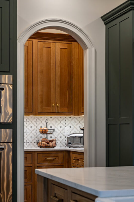 Quartersawn White Oak Natural pantry cabinets viewed through an arched walkway.