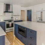Blue and white kitchen cabinets with white appliances.