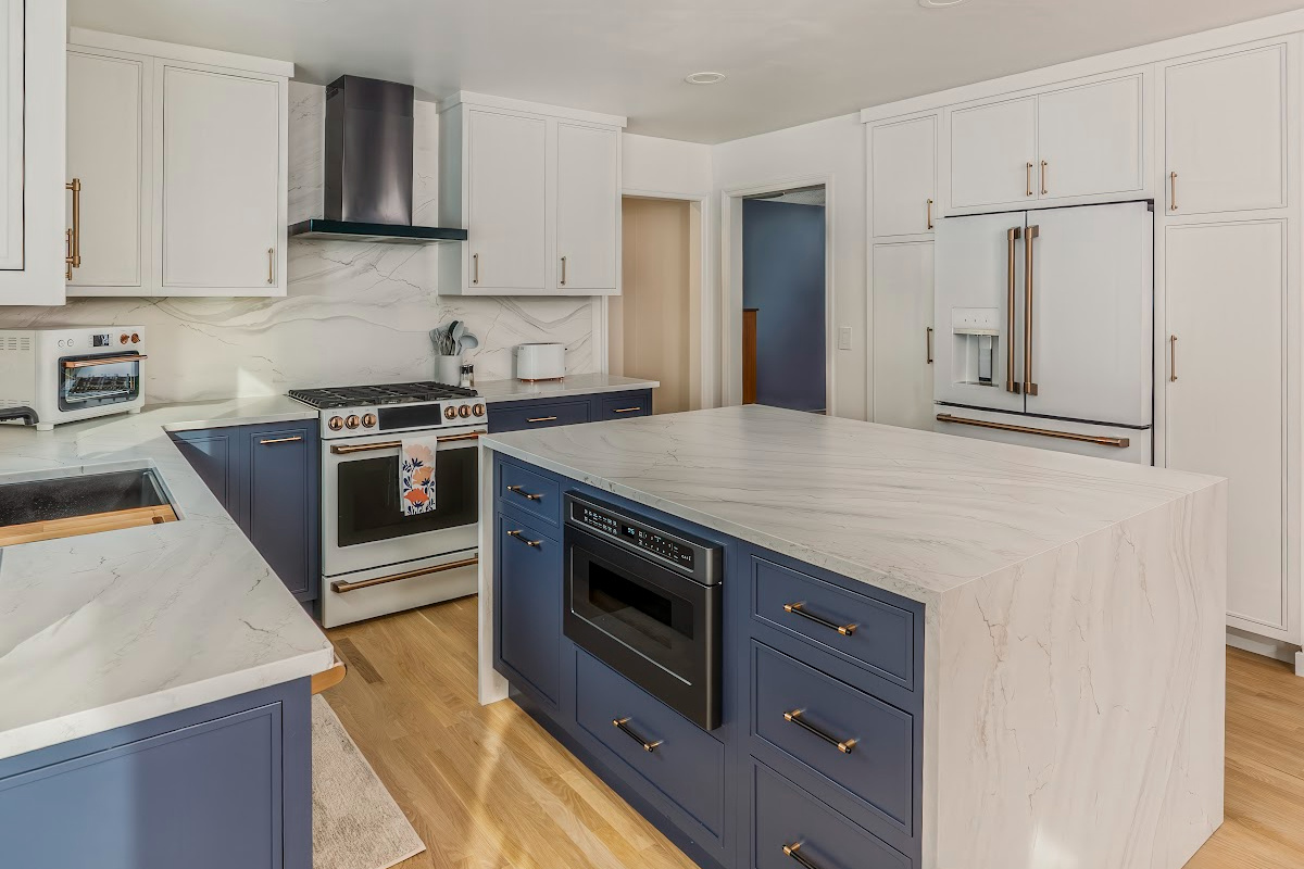 Blue and white kitchen cabinets with white appliances.