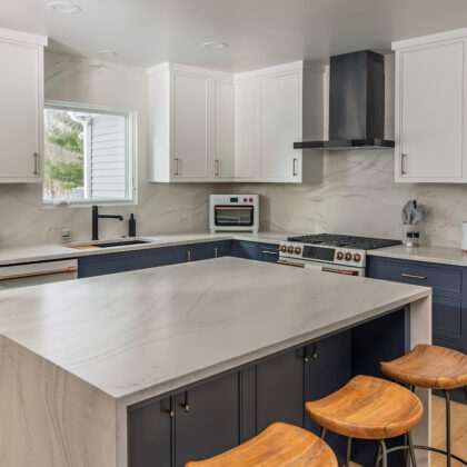 Blue and white kitchen cabinets with white appliances.