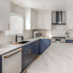 Blue and white kitchen cabinets with white appliances.