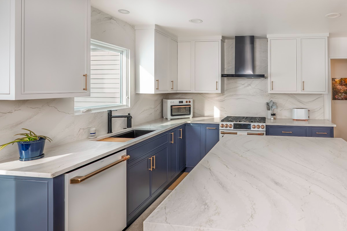 Blue and white kitchen cabinets with white appliances.