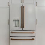White kitchen cabinets with white fridge.