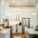 White kitchen perimeter cabinets with brown island.
