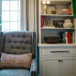 White bookcase cabinet with drawer and doors next to a blue couch.