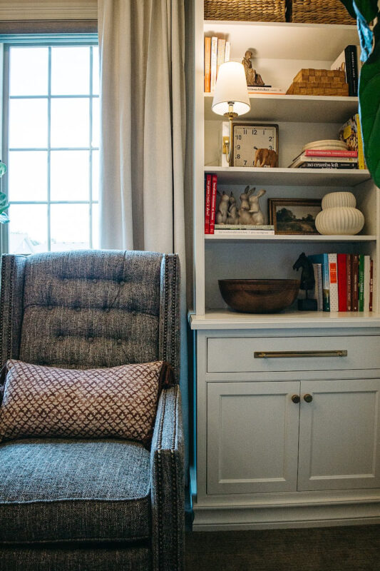 White bookcase cabinet with drawer and doors next to a blue couch.