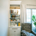 White bookcase cabinet with drawer and doors next to a blue couch.