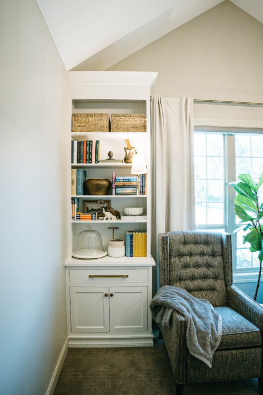 White bookcase cabinet with drawer and doors next to a blue couch.