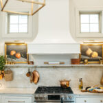 White kitchen cabinets and curved chimney range hood.
