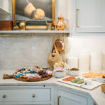White kitchen cabinets with appetizers on the counter.