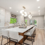 Beige painted kitchen perimeter cabinets with a 16-foot stained quartersawn white oak island wtih seating.