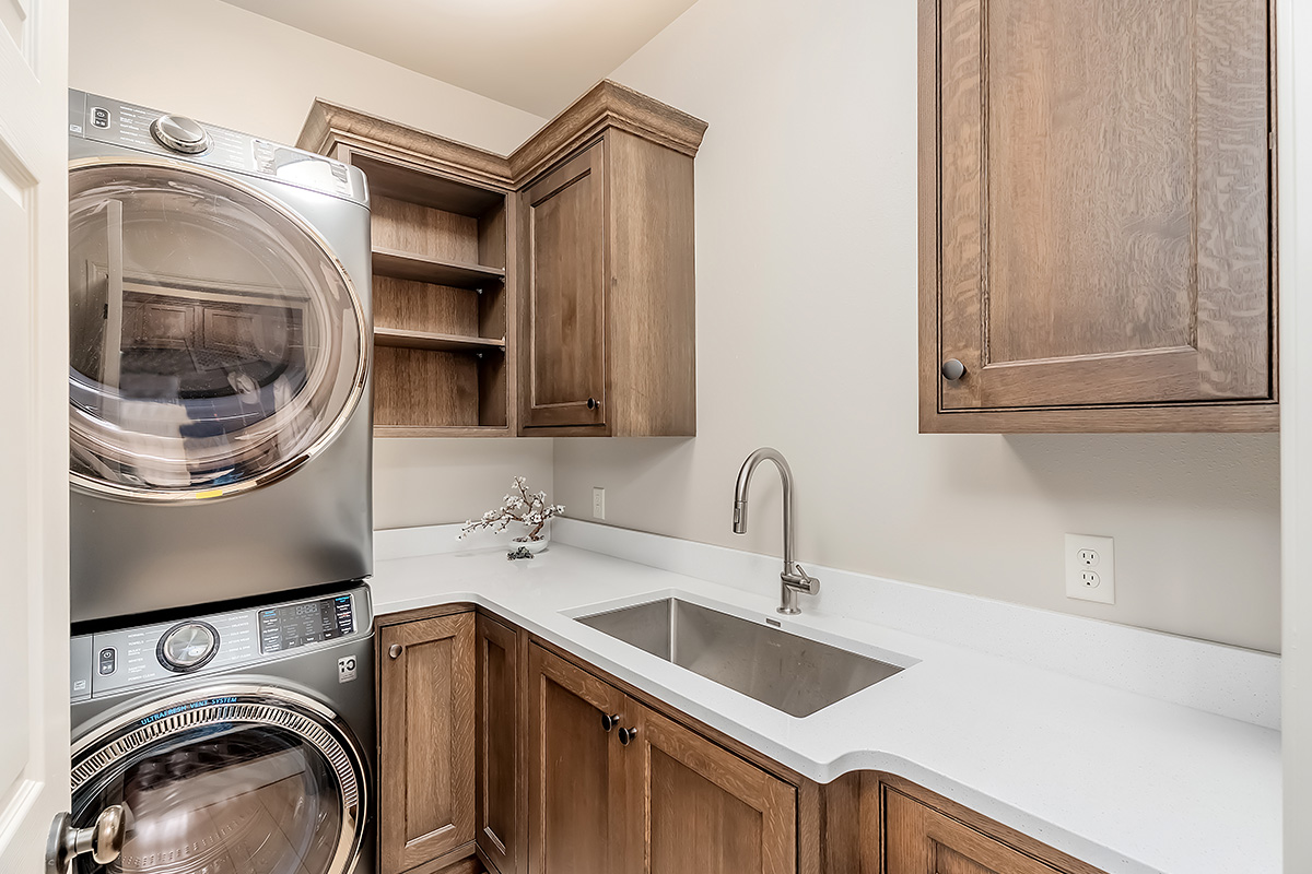 Brown stained laundry room with stacked washer and dryer