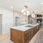 Beige painted kitchen perimeter cabinets with a 16-foot stained quartersawn white oak island wtih seating.
