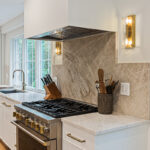 White painted kitchen cabinets and large hood above stove.