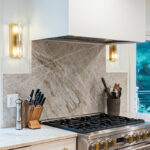 White painted kitchen cabinets and large hood above stove.